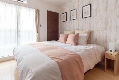 a bedroom with a large white bed with pink pillows at FDS Liberta in Osaka