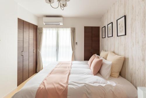 a bedroom with a large bed with pink and white pillows at FDS Liberta in Osaka