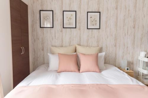 a bedroom with a white bed with pink pillows at FDS Liberta in Osaka