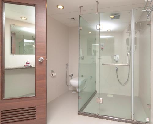 La salle de bains est pourvue d'une douche en verre et de toilettes. dans l'établissement Nanutel Margao, à Madgaon