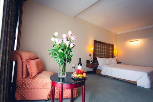 a hotel room with a bed and a table with flowers at Hotel Cambodiana in Phnom Penh
