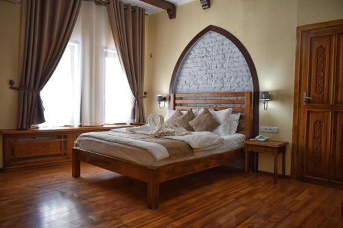 Schlafzimmer mit einem großen Bett mit einem Kopfteil aus Holz in der Unterkunft Hotel Malika Bukhara in Buxoro