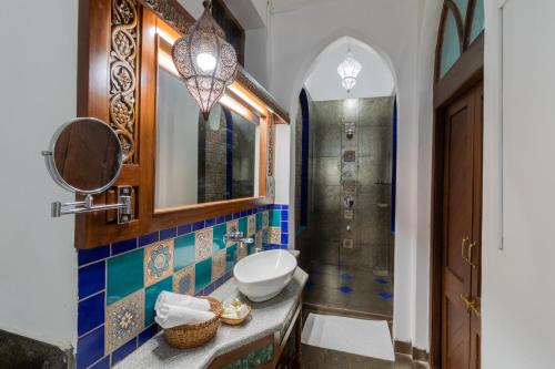 une salle de bain avec un lavabo, un miroir et une douche dans l'établissement Madhav Bagh - Royal Heritage Stay, à Vadodara