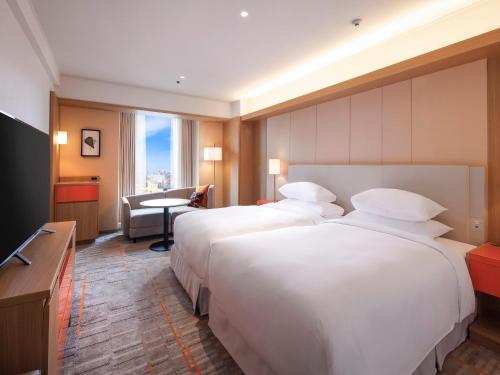 a hotel room with two beds and a table at Sheraton Miyako Hotel Osaka in Osaka