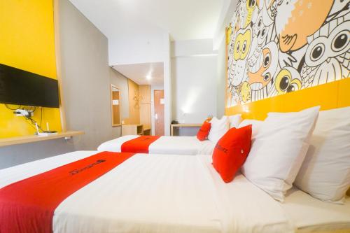 a bedroom with two beds with orange and white pillows at RedDoorz Apartment near Bundaran Satelit Surabaya in Surabaya