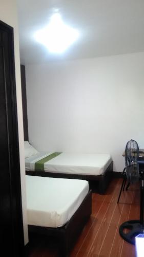 two beds in a room with a light on the ceiling at Lipa Bed & Breakfast in Lipa