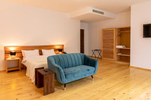 a bedroom with a bed and a blue chair at Hotel Posta in Mestia