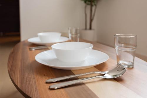 a wooden table with two white plates and a glass at FDS Liberta in Osaka
