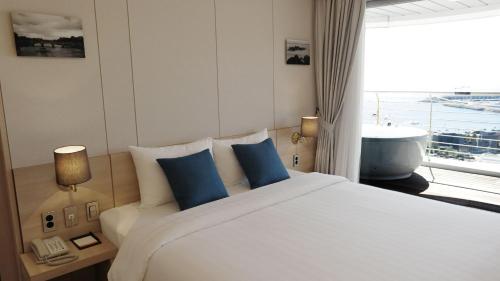 a bedroom with a large bed with blue pillows and a window at Hotel bridge Seogwipo in Seogwipo