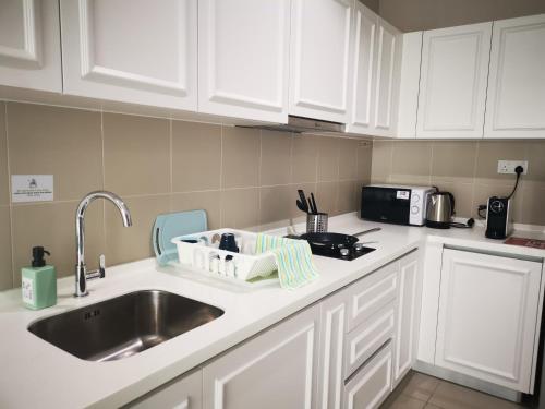 a kitchen with white cabinets and a sink at Host Assist Homestay by HA i-City in Shah Alam