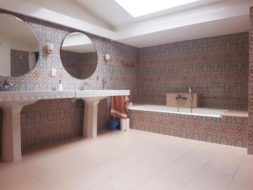 a bathroom with a tub and a sink and mirrors at Rooftop Apartment in Bad Hofgastein