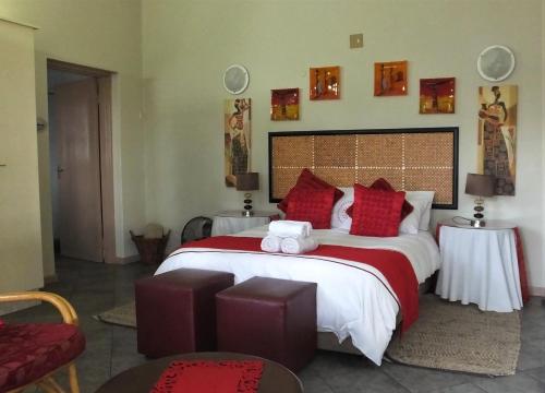 a bedroom with a large bed with red pillows at Tatenda Guest House in Hazyview