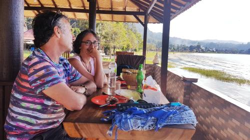a man and a woman sitting at a table at Batur Green Lakeview in Kintamani Bali in Kintamani