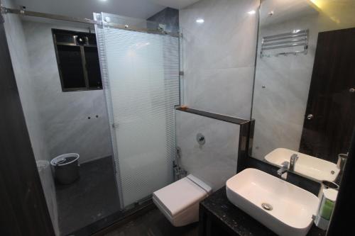 a bathroom with a toilet and a sink and a shower at Green Arc Homestay in Malvan