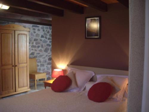 a bedroom with a bed with red pillows at ferme de Lamourio in Saint-Cernin