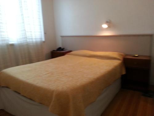 a bedroom with a bed with a yellow blanket on it at Hotel Isis in Buenos Aires
