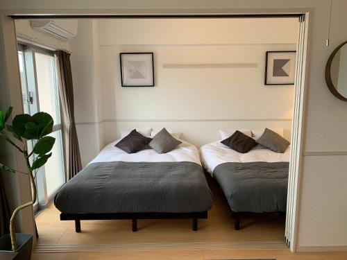 two beds in a room with a mirror at Allstay CHIBANA in Okinawa City