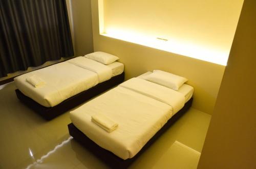 two beds in a room with a light on the wall at Chiangdaoplace in Chiang Dao