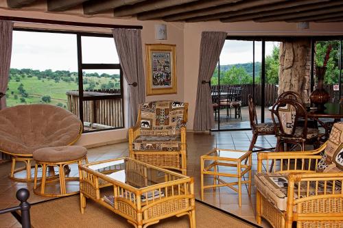 a living room with chairs and tables and windows at Mahikeng Lodge in Magaliesburg
