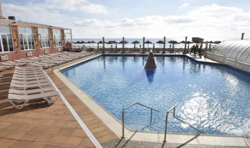 a large swimming pool with chairs and umbrellas on a building at Hotel & Spa Entremares in La Manga del Mar Menor