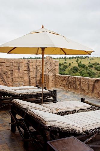 two beds with an umbrella on a patio at Mahikeng Lodge in Magaliesburg