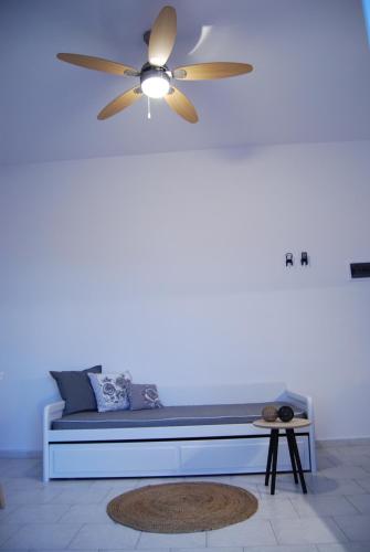 a ceiling fan in a white room with a bench at Galini Rooms & Apartments in Finikas