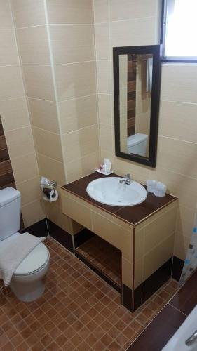 a bathroom with a sink and a toilet and a mirror at Iyara Hua Hin Lodge in Hua Hin