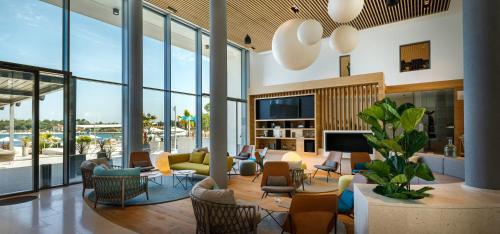a living room with a couch and chairs and a tv at Marea Suites, Valamar Collection in Poreč