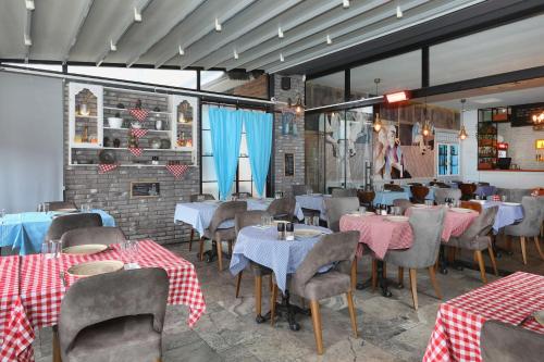 a restaurant with tables and chairs with red and white tablecloths at New Balturk Hotel Izmit in Kocaeli
