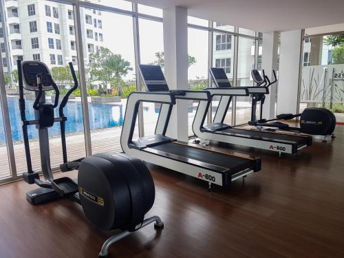 a row of treadmills in a gym with a large window at Minimalist 2BR Apartment at M-Town Residence By Travelio in Tangerang