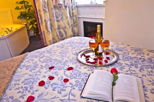 a bed with a book and two glasses of wine at Elk Forge Bed and Breakfast in Elkton