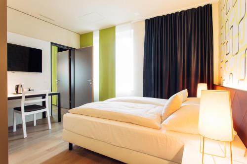 a bedroom with a bed and a desk and a computer at harry's home Zürich-Wallisellen in Wallisellen