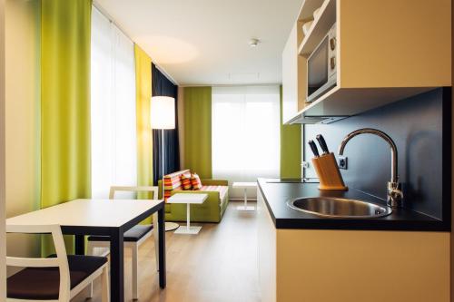 a kitchen with a sink and a living room at harry's home Zürich-Wallisellen in Wallisellen