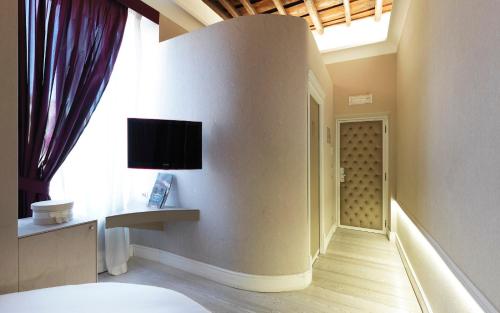 a room with a tv on the wall next to a window at LE RÊVE DE NAIM Roma in Rome