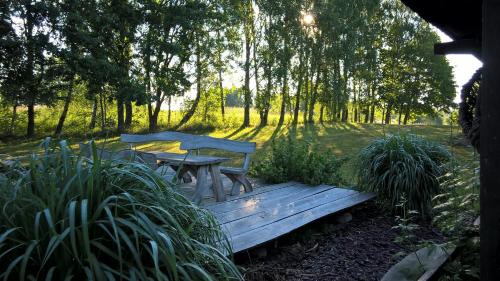 a wooden bench and table in a garden with trees at Kačiūniškis in Kaciūniškiai
