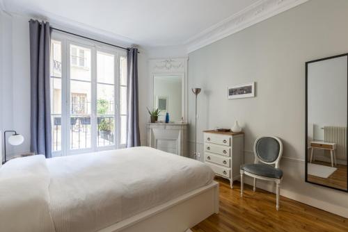 a white bedroom with a bed and a chair at Veeve - Eiffel Elegance in Paris