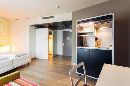 a small room with a bed and a kitchen at harry's home Zürich-Wallisellen in Wallisellen