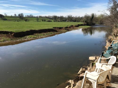 two white chairs sitting next to a river at Domaine BORCHAMPS. in Saint-Nizier-sous-Charlieu