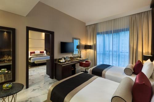 a hotel room with two beds and a television at Millennium Place Dubai Marina in Dubai