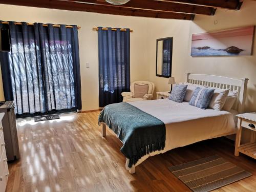a bedroom with a bed and a chair and windows at Tortoise Trail Lodge in Langebaan