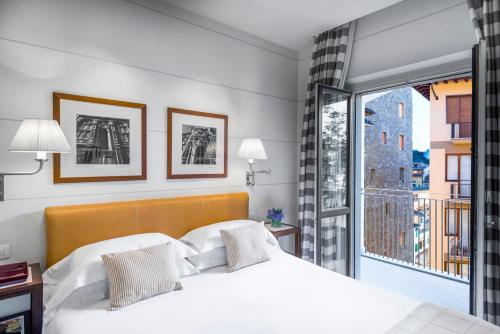 a bedroom with a white bed and a balcony at Gallery Hotel Art - Lungarno Collection in Florence