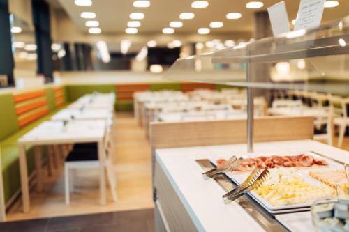 a restaurant with a counter with food on a plate at harry's home Zürich-Wallisellen in Wallisellen