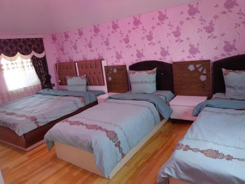 a room with three beds and pink walls at Tubram S Ailəvi Qonaq Evi in Sheki