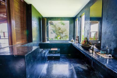 a large bathroom with a large tub with blue walls at Villa Tao in Tabanan