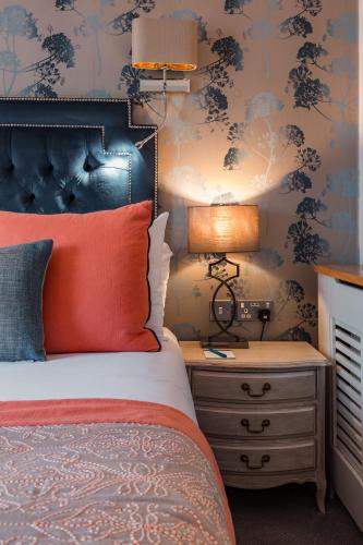 a bedroom with a bed and a night stand with a lamp at Thornton Hall Hotel & Spa in Heswall