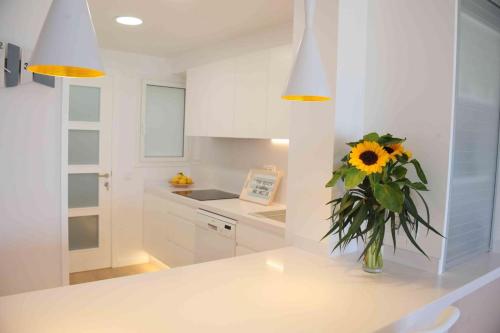 a white kitchen with a vase with a sunflower in it at Apartamento frente al mar in Canet de Mar