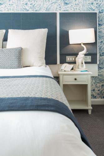 a bedroom with a bed and a table with a lamp at Thornton Hall Hotel & Spa in Heswall