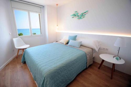 a bedroom with a bed and a table and a window at Apartamento frente al mar in Canet de Mar