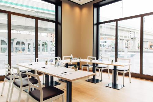 a row of tables and chairs in a restaurant with large windows at harry's home Zürich-Wallisellen in Wallisellen