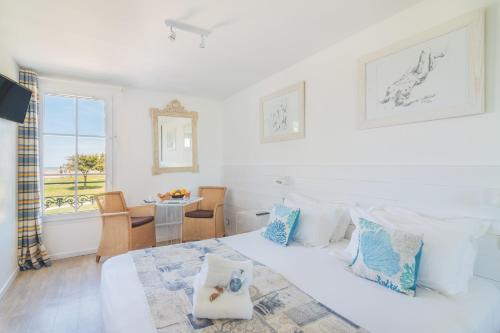 a white bedroom with a bed and a table at Le Clos Du GALION - Ile de Ré in Saint-Martin-de-Ré